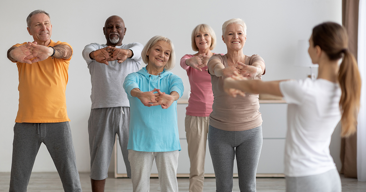 A group of diverse older adults taking a fitness class led by a young woman.