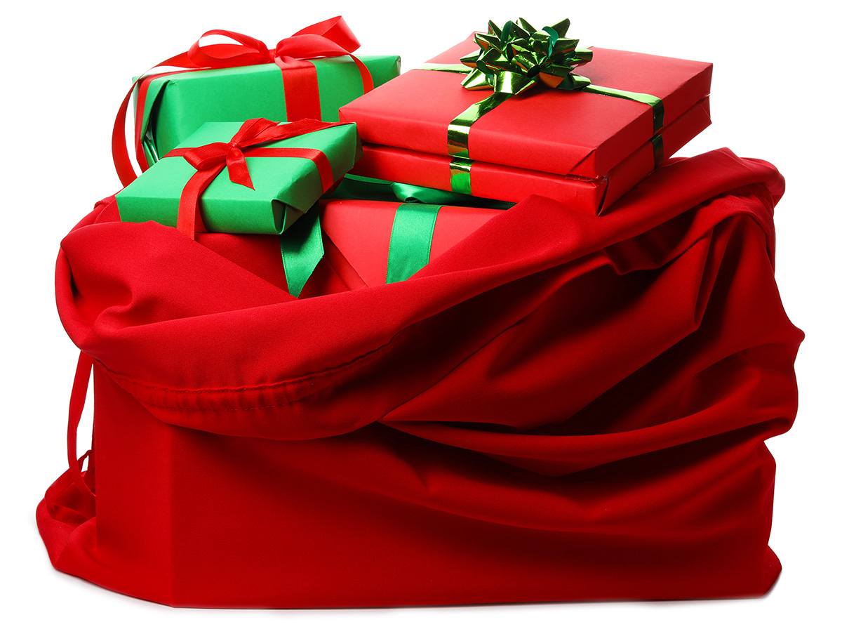 A large red velvet bag filled with wrapped holiday gifts.