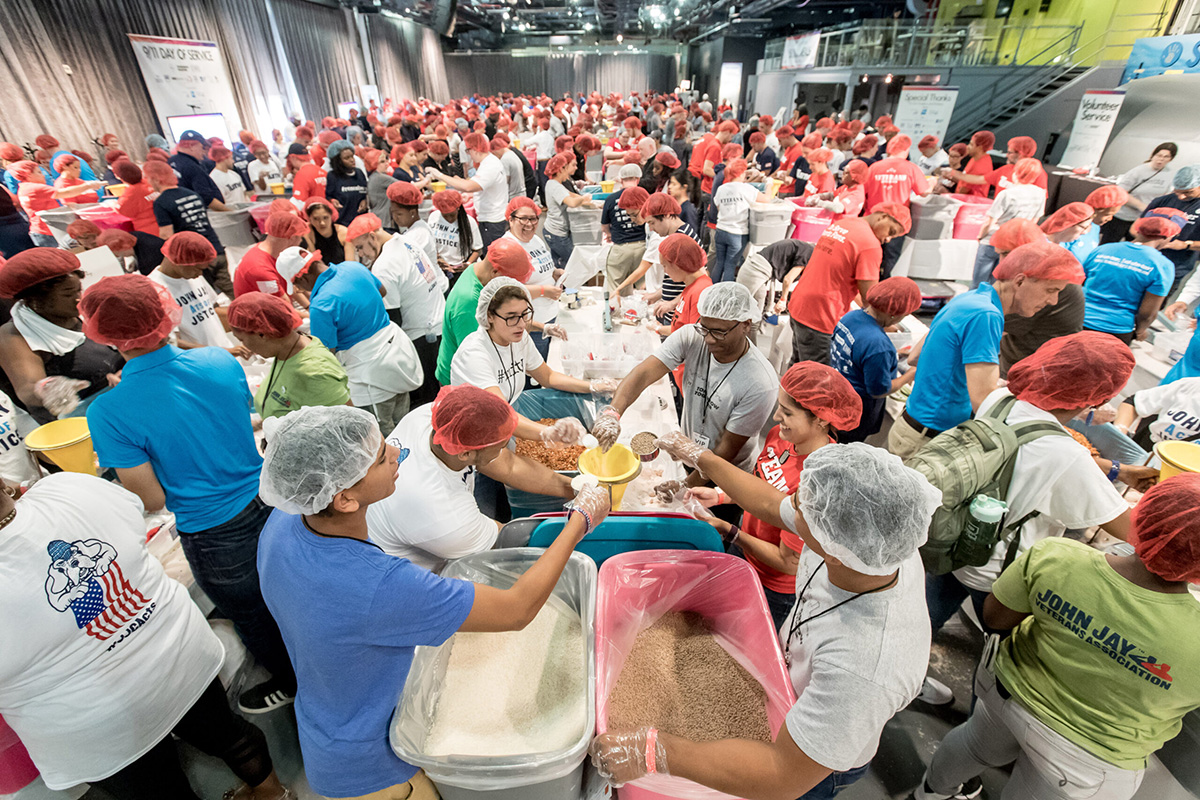 A large room full of volunteers pack meals for food pantries.