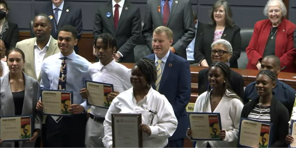 Image of award winners holding up their certificates with members of the board 