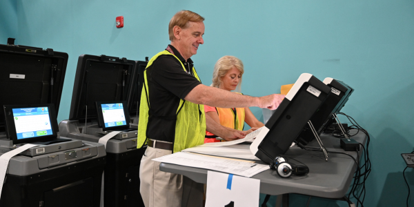 Image of election officers operating a ballot scanner.  Image of election officers operating a ballot scanner.