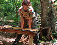 Boy Scout building a bench out of tree stumps